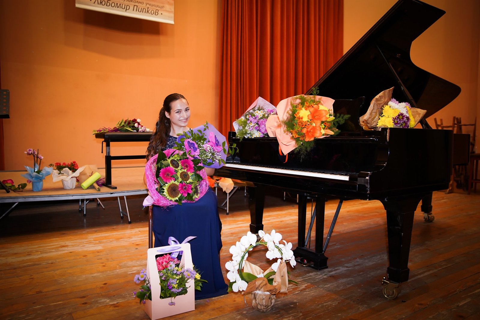 Angela Todorova on stage with bouquets after a recital at the “Lubomir Pipkov” school