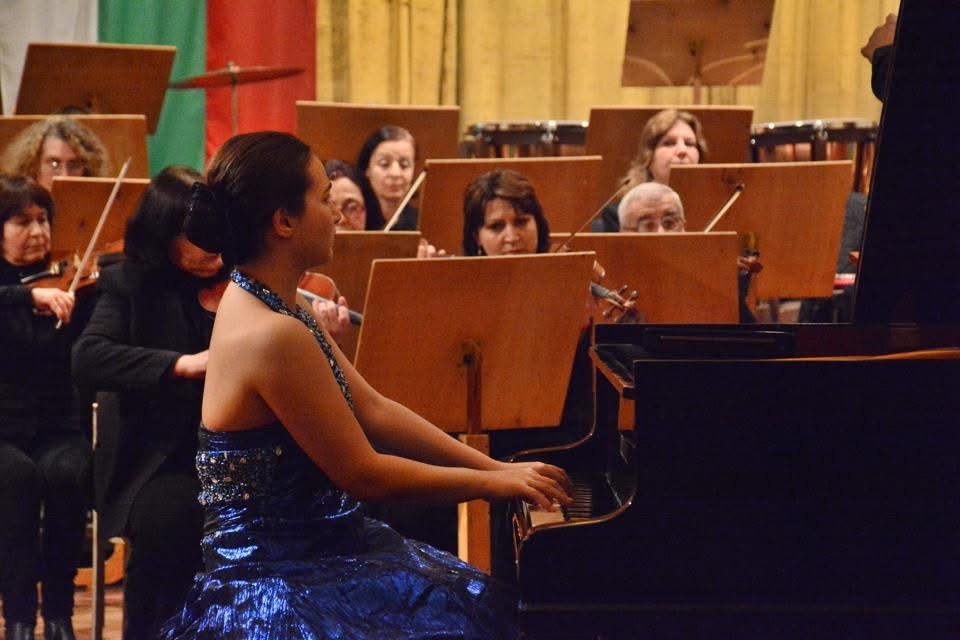 Angela Todorova at the grand piano with the orchestra behind her